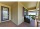 Cozy front porch features a comfortable seat and a decorative glass front door with brick pavers at 10015 Marbella Dr, Bradenton, FL 34211