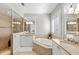 Bright bathroom featuring dual sinks, vanity, soaking tub, tiled floors, and plantation shutters at 11716 Strandhill Ct, Lakewood Ranch, FL 34202