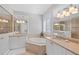 Bright bathroom featuring dual sinks, vanity, soaking tub, tiled floors, and plantation shutters at 11716 Strandhill Ct, Lakewood Ranch, FL 34202
