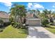 Charming single-story home with a well-manicured lawn, mature palms, and a brick driveway at 11716 Strandhill Ct, Lakewood Ranch, FL 34202
