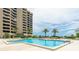 Beautiful swimming pool and condominium building with palm trees and a blue sky at 1211 Gulf Of Mexico Dr # 309, Longboat Key, FL 34228