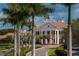 View of the clubhouse with stately columns and lush landscaping on a sunny day at 13 Bayhead Ln, Osprey, FL 34229