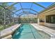 Screened pool with rock waterfall feature surrounded by lush landscaping at 13 Bayhead Ln, Osprey, FL 34229