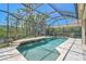 Screened pool with rock waterfall feature surrounded by lush landscaping at 13 Bayhead Ln, Osprey, FL 34229