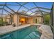 Screened pool with rock waterfall feature surrounded by lush landscaping and patio at 13 Bayhead Ln, Osprey, FL 34229