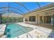 Screened pool with rock waterfall feature surrounded by lush landscaping and patio at 13 Bayhead Ln, Osprey, FL 34229