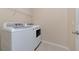 A well lit laundry room with a white washer and dryer, with a shelf at 15118 Agave Grove Pl, Bradenton, FL 34212