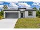 Modern home with a gray garage door, well-maintained lawn, and classic black trimmed entry at 158 Chickering St, Port Charlotte, FL 33954