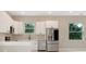 The modern kitchen has white cabinets, stainless steel appliances, and abundant natural light at 158 Chickering St, Port Charlotte, FL 33954