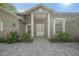 Inviting front entrance with a stylish gray facade, decorative columns, and manicured garden beds at 1693 Landings Ln, Sarasota, FL 34231