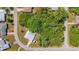 Aerial view of a vacant lot surrounded by trees, neighboring houses, and paved streets at 18399 Burkholder Cir, Port Charlotte, FL 33948