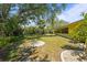 Lush backyard with green lawn, mature trees, and a peaceful, private setting at 18399 Burkholder Cir, Port Charlotte, FL 33948