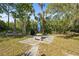 Private backyard seating area with a picnic table, a sun umbrella, and shaded by lush greenery at 18399 Burkholder Cir, Port Charlotte, FL 33948