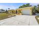 Inviting yellow home with arched entryways, beautiful landscaping and long driveway at 18399 Burkholder Cir, Port Charlotte, FL 33948