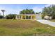 Inviting yellow home boasts a well-manicured lawn and arched entryway at 18399 Burkholder Cir, Port Charlotte, FL 33948