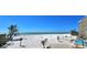 Expansive beach view featuring white sands, gentle waves and swaying palm trees under a clear blue sky at 20 Whispering Sands Dr # 406, Sarasota, FL 34242