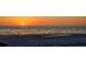 Sunset on a beach with calm waters and people enjoying the scene, framed by a palm tree's silhouette at 20 Whispering Sands Dr # 406, Sarasota, FL 34242