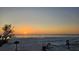 Beach sunset view with serene ocean, lined with beach chairs and palm trees under a vibrant sky at 20 Whispering Sands Dr # 406, Sarasota, FL 34242