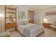 Bright bedroom featuring a bed with light blue accents, wooden shelving, and artwork at 20 Whispering Sands Dr # 406, Sarasota, FL 34242
