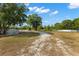 A sprawling property with open space, mature trees, and a gravel driveway leading to the build site at 22520 61St E Ave, Bradenton, FL 34211