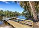 Picturesque view of a wooden dock on a tranquil river, surrounded by lush vegetation and a clear blue sky at 2707 162Nd E Ave, Parrish, FL 34219
