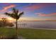 A backyard sunset water view framed by a palm tree and grassy lawn at 327 Riverpoint Ne Dr, Bradenton, FL 34208