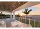 A covered balcony with a sunset water view, comfortable seating, and modern railings at 327 Riverpoint Ne Dr, Bradenton, FL 34208