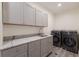 Well-equipped laundry room with gray cabinets, marble countertops, and modern washer/dryer at 327 Riverpoint Ne Dr, Bradenton, FL 34208