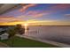 A waterfront sunset view of the dock from the manicured lawn and palm tree at 327 Riverpoint Ne Dr, Bradenton, FL 34208