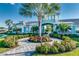 Community clubhouse entrance featuring a tropical design with palm trees, landscaping, and a decorative archway at 3520 Woodmont Dr, Parrish, FL 34219