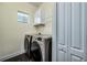 Modern laundry room with a washer and dryer set, dark tile flooring, and overhead white cabinets at 3520 Woodmont Dr, Parrish, FL 34219