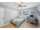 This bedroom features two windows, a ceiling fan, a bed, a desk and chair, a rug, and some artwork at 3828 20Th N St, St Petersburg, FL 33714