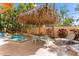 Tropical backyard oasis features a pool with a waterfall, a tiki hut, and an outdoor dining set at 4001 5Th Ave, Holmes Beach, FL 34217