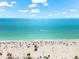 Vibrant beach scene featuring white sand, clear turquoise water, and beachgoers enjoying the sun at 4001 5Th Ave, Holmes Beach, FL 34217