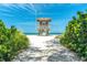 Scenic beach view leading to the lifeguard station with lush greenery, clear blue skies, and a sandy beach at 4001 5Th Ave, Holmes Beach, FL 34217