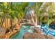 Custom pool features rock waterfall, lush landscaping, and tiki hut, creating a private oasis at 4001 5Th Ave, Holmes Beach, FL 34217