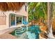 This custom pool area features a rock waterfall, lush landscaping, and a tiki hut with seating at 4001 5Th Ave, Holmes Beach, FL 34217