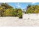 Gravel drive with white picket fence and gate surrounded by mature bushes and trees at 424 62Nd St, Holmes Beach, FL 34217