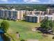 Scenic aerial view of the condo buildings overlooking a lush golf course with players and a water feature at 4440 Fairways Blvd # 210, Bradenton, FL 34209