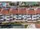 An aerial view shows private balconies, lush greenery, and a tennis court for condo residents at 5055 Gulf Of Mexico Dr # 422, Longboat Key, FL 34228