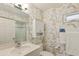 Bright bathroom featuring a sink, toilet, walk-in shower, storage cabinet, and a window, all adorned with unique wallpaper at 5055 Gulf Of Mexico Dr # 422, Longboat Key, FL 34228