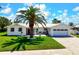 Charming single-story home features a well-manicured lawn and a two-car garage, complemented by a lush palm tree at 527 Key Royale Dr, Holmes Beach, FL 34217