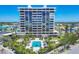 Exterior image of a modern condo building with a beautiful pool and palm trees at 5300 Ocean Blvd # 202, Sarasota, FL 34242