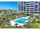 Aerial view of a sparkling pool surrounded by palm trees and lush landscaping in a sunny setting at 5300 Ocean Blvd # 202, Sarasota, FL 34242