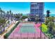Outdoor tennis court alongside high rise condo buildings, American flag, and lush landscaping at 5300 Ocean Blvd # 202, Sarasota, FL 34242