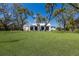 Sprawling backyard with a manicured lawn, mature trees, and classic white home exterior at 5307 22Nd W Ave, Bradenton, FL 34209