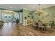 Open-concept dining room featuring wood floors, a chandelier, and views of the front entry and living area at 5329 Trails Bend Ct, Sarasota, FL 34238