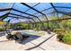 Screened-in pool area featuring a waterfall, sun loungers, an umbrella, and lush landscaping creating a private oasis at 5329 Trails Bend Ct, Sarasota, FL 34238