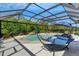 A beautiful screened pool area with a waterfall, hammock, sun loungers, and lush landscaping creating a tranquil outdoor space at 5329 Trails Bend Ct, Sarasota, FL 34238