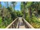 Wood walkway over natural scenery leads to a metal fence that offers an element of privacy and blends the house with nature at 5329 Trails Bend Ct, Sarasota, FL 34238